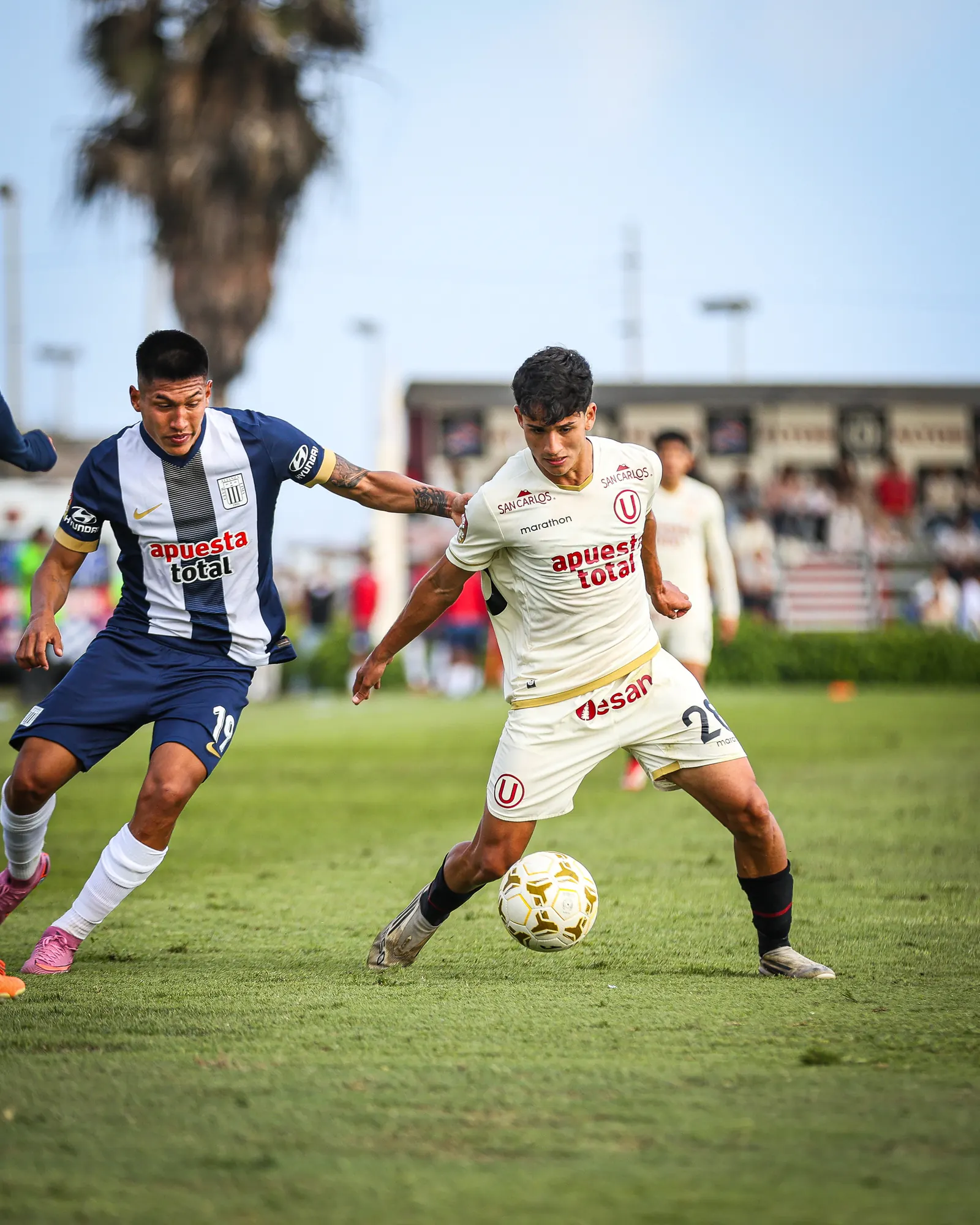 Dos futbolistas juveniles disputan el balón en un partido.